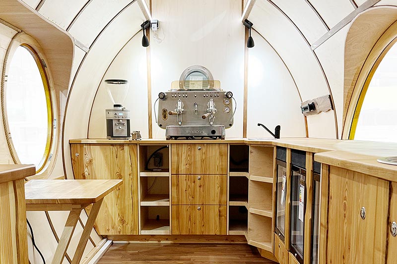Holzwagen als Kaffeebar: Theke und Einbauten aus Holz, Siebträgermaschine und Geräte im Innenraum.